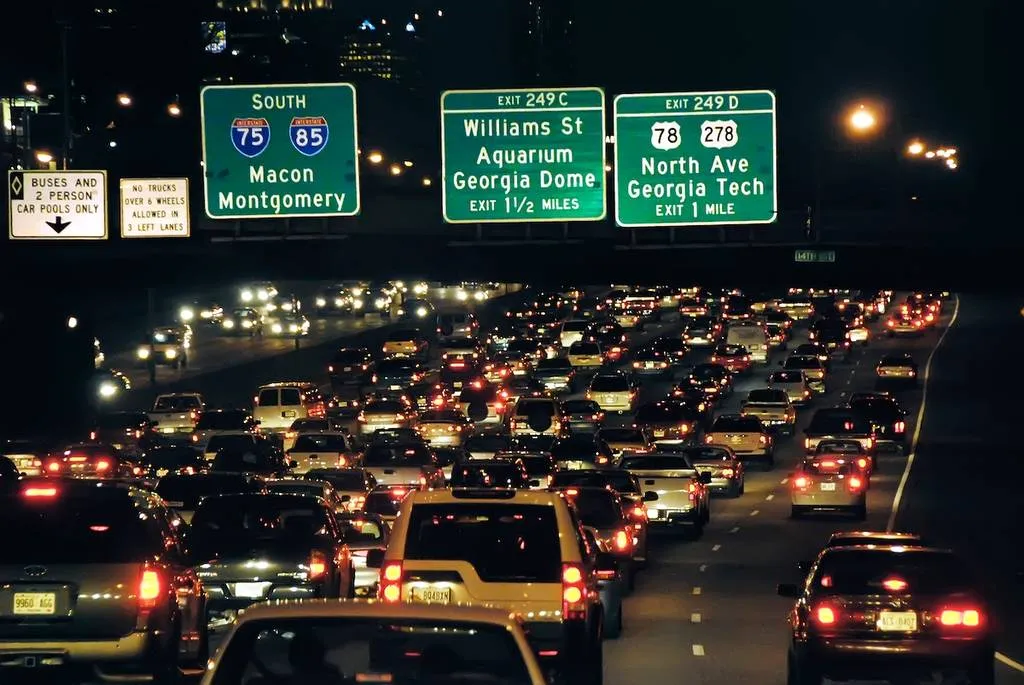 Atlanta I-75 and I-85 Downtown Connector at night with glowing brake lights and signs for Macon, Montgomery, Georgia Dome, and Georgia Tech