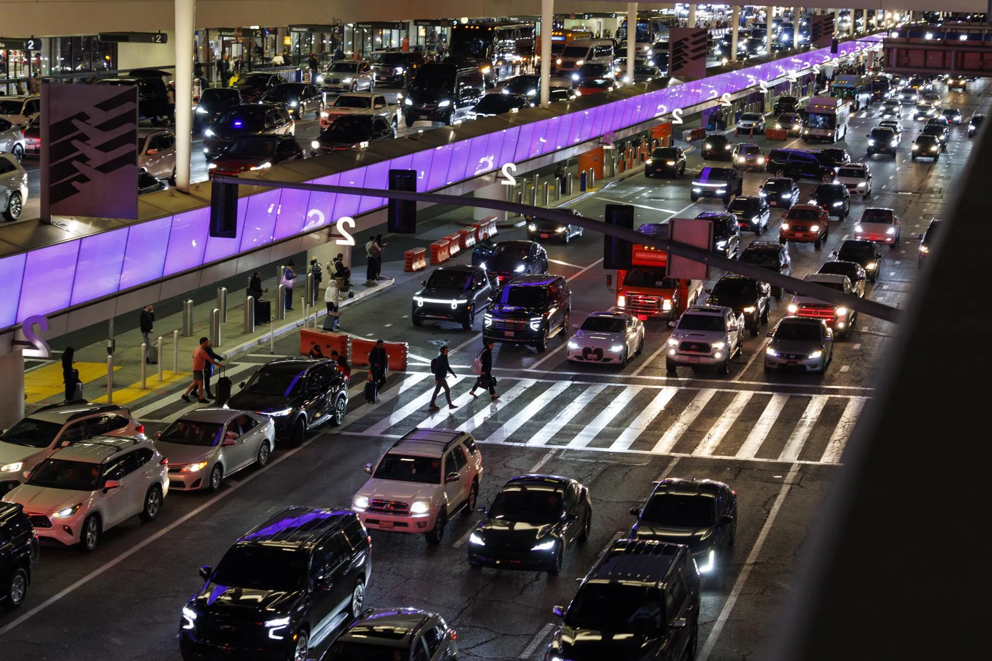 LAX airport terminal at night with heavy vehicle traffic and purple lighting